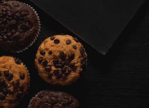 A closeup shot of  delicious chocolate and vanilla muffins with chocolate chips on a black background
