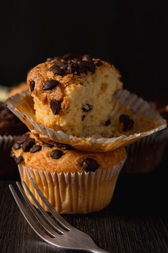 A vertical closeup shot of  delicious vanilla muffins with chocolate chips on a black background