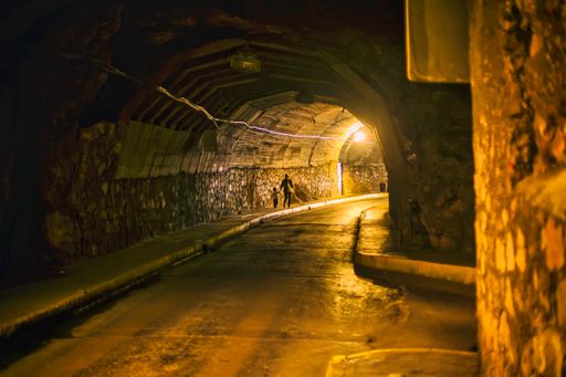 A back view of mother and child walking on a sidewalk in a tunnel at night in Guanajuato