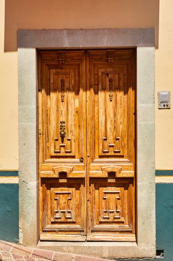 A vertical shot of an old closed wooden entrance door to a building on a sunny day