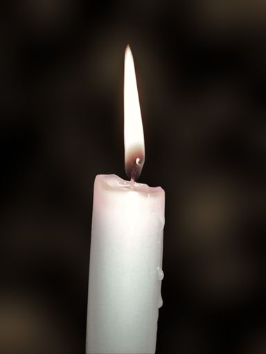 A vertical shot of a white candle glowing in the dark