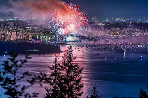 A beautiful shot of bright colorful exploding fireworks in a city over water