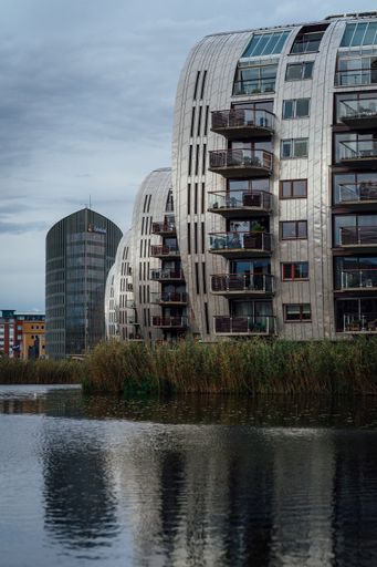 A vertical shot of modern apartment buildings overlooking a lake  on blue sky background
