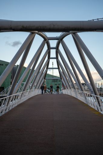 A vertical shot of bicycles riding on the bridge over the Oosterdok in Amsterdam