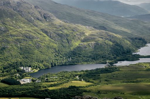 A landscape of the hills covered in greenery under a cloudy sky in Connemara National Park, Ireland
