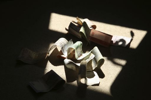 Various banknotes from around the world on a floor surrounded by shadows. Global economic crisis concept image.