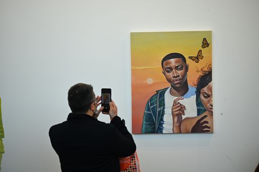 A back view of a man taking a picture of a painting during the contemporary art fair "Artissima" in Turin