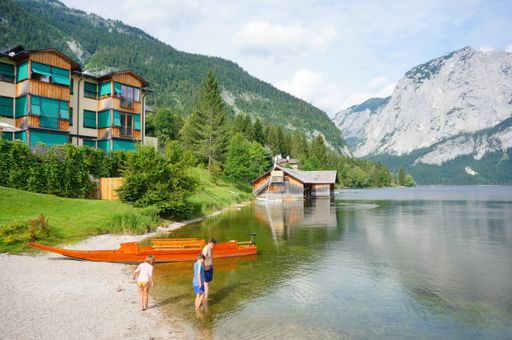 A group of tourists at the lakeshore against the hotel buildings and mountain landscape in Aultaussee, Austria