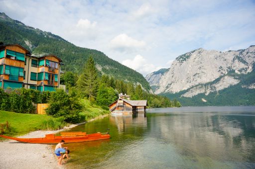 A couple of tourists at the lakeshore against the hotel buildings and mountain landscape in Aultaussee Austria