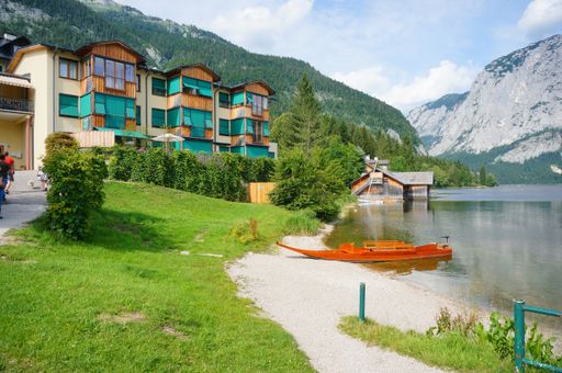A hotel building by a lake and mountains in Aultaussee, Austria