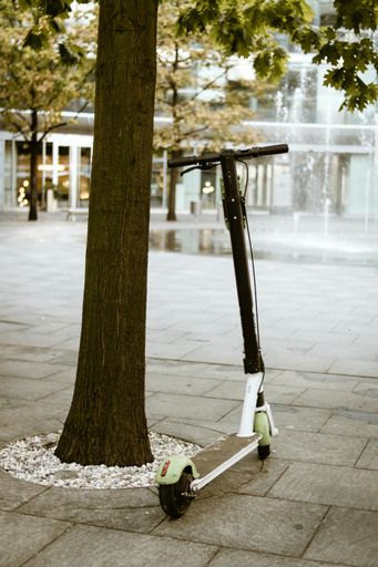 A vertical shot of an electric scooter and a fountain on the background