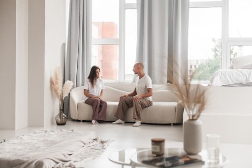 Young Russian yoga partners talking while sitting on a couch in a white studio