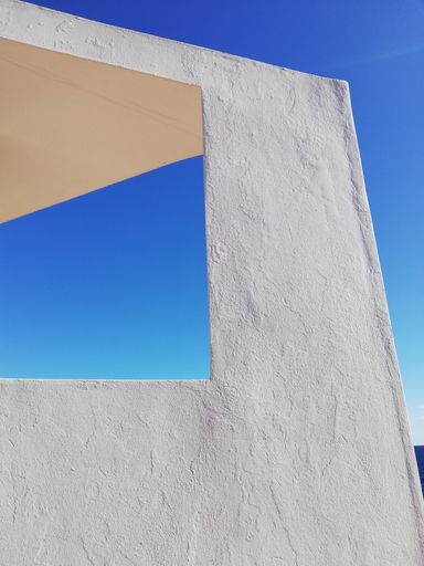 A vertical shot of a white textured wall over a blue sky