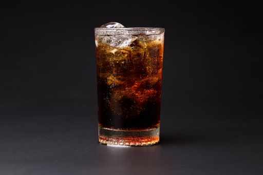 A closeup of a Cola in glass with clear ice cubes isolated on black background