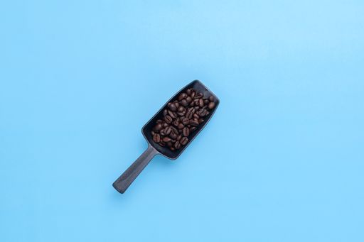 A top view of coffee beans on a blue background with a copy space