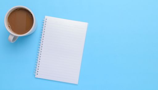 A top view of a coffee mug, book on a blue background with a copy space