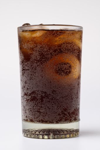 A close up of a Cola in glass with clear ice cubes isolated on white background