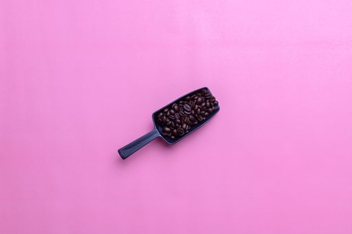 A top view of coffee beans on a pink background with a copy space