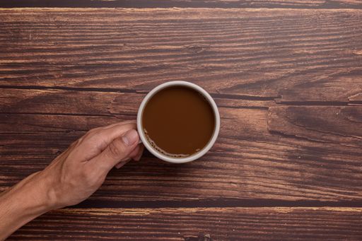 A top view of a  Hand holding a coffee mug on a wood background