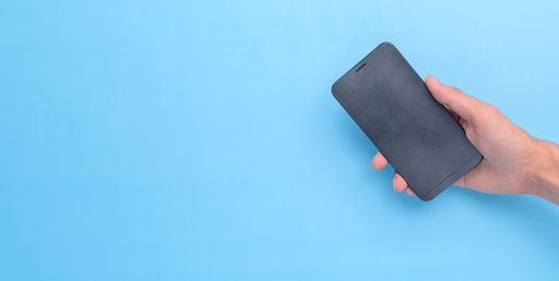 A top view of a hand holding a smartphone on a blue background with a copy space