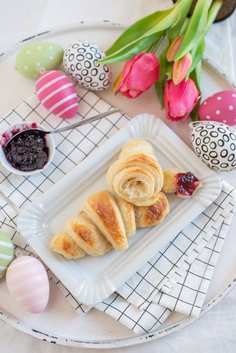 A vertical closeup of a delicious breakfast with croissant and jam