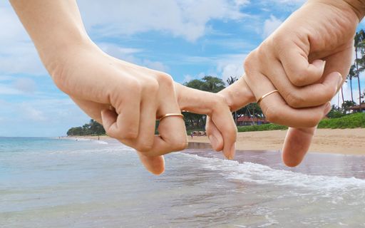 A closeup shot of a married couple holding each other's fingers