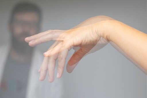 Doctor who is examining a patient with hand tremors due to Parkinson's disease. Blurred effect made with a double exposure