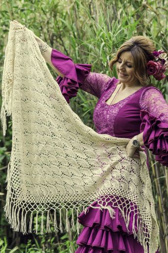 A vertical shot of a middle-aged smiling woman in a pink dress holding a beige scarf