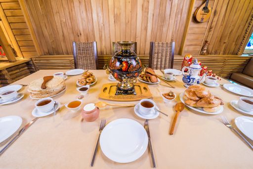 A high angle shot of a served food, plates, utensils and cups of tea on a dining table