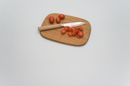 datterini tomatoes with chopping board and knife on a white surface with text space