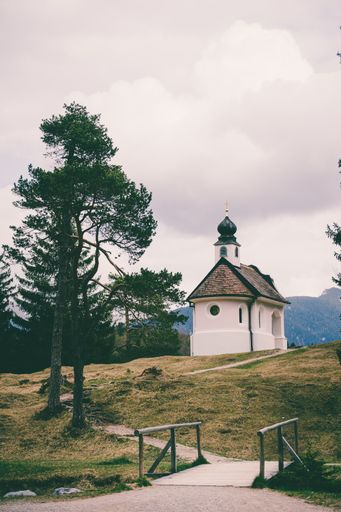 A beautiful small catholic church in the mountains of the Bavarian Alps near the Lautersee and Mittenwald. Cloudy mountain panorama