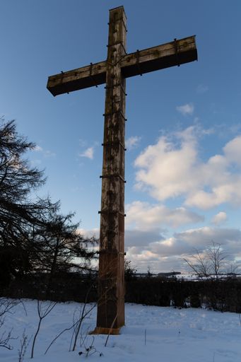 huge wooden cross on the top of the hill in winter in snow, vetical shot, in german town plon, ploen