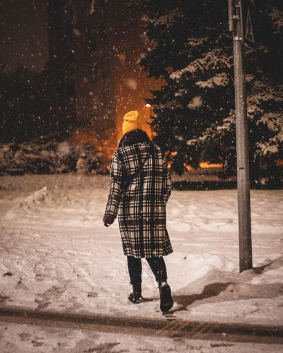 A vertical shot of a beautiful woman walking through the snowy woodland