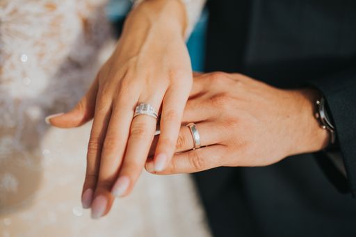 A closeup shot of the hands of newly married groom and the bride holding hands and wearing rings
