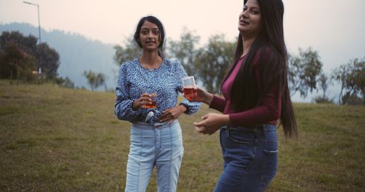 The young women enjoy their time with drinks in the yard.