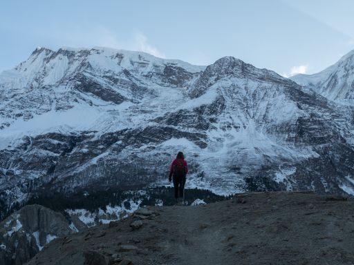 A behind shot of the hiker and the mesmerizing view of the mountains covered in snow in Nepal