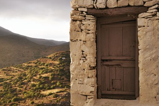 A closeup shot of a stone house surrounded by hills in Amorgos Island, Greece at sunset