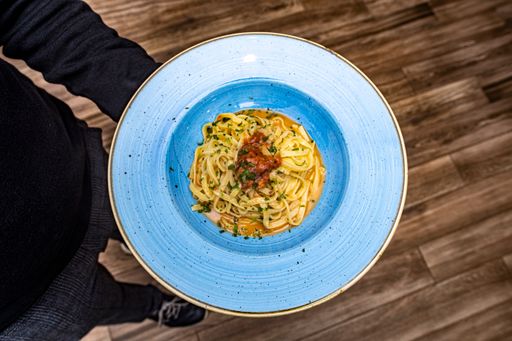 A top view of a tasty cooked Pasta Rizzi with red sauce in a plate in a waiter's hand