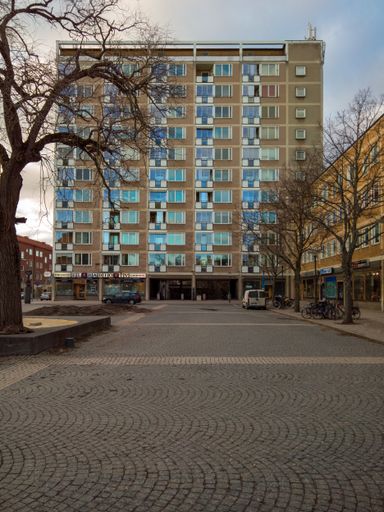 A beautiful shot of a building with blue windows and pavement in front of it