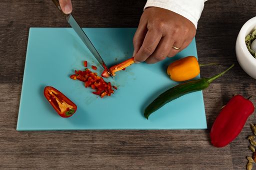 A closeup of the chef's hands cutting vegetables.