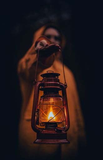 A vertical shot of a young man in a yellow hoodie holding a lantern
