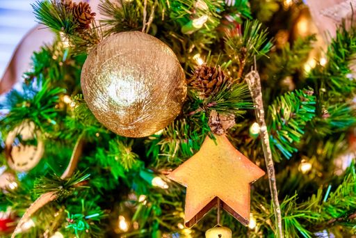 A beautiful closeup of a golden ball and other decorations on a Christmas tree with lights