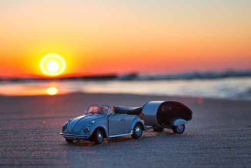 A closeup shot of a Volkswagen Car mini model on a beach at sunset