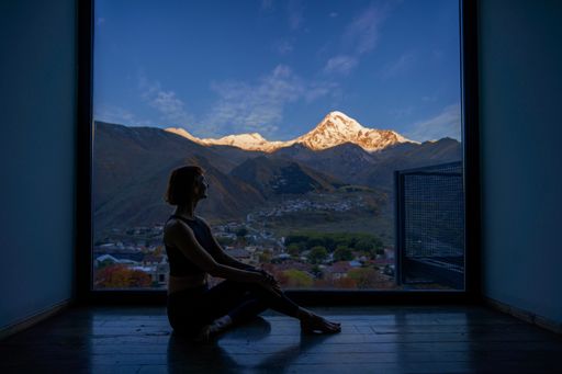 An amazing view of a caucasian woman doing yoga against Caucasus mountains  background