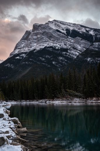 A beautiful view of Pigeon Mountain with water in Alberta, Canada against a cloudy sky
