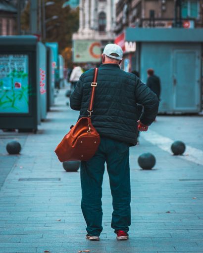 A vertical shot of a male walking down the street during the day