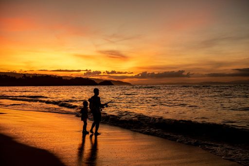 A beautiful shot of a parent and a child standing on the beach during the sunset