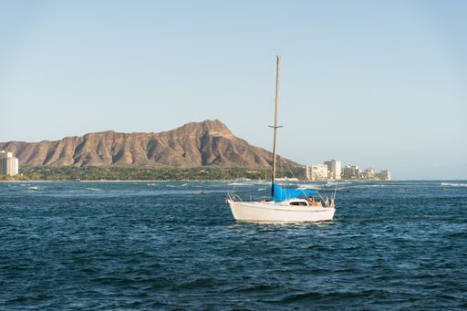 A bright summer day in Honolulu, Hawaii with a sailboat in the clear blue ocean waters