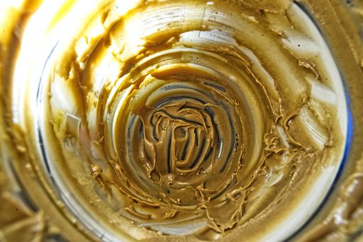 An overhead closeup shot of a jar with a very little cream left on the bottom and on the walls