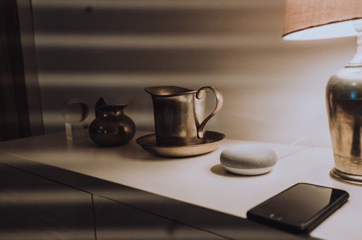 The mobile phone, old metallic bowls, smart speaker, and lampshade